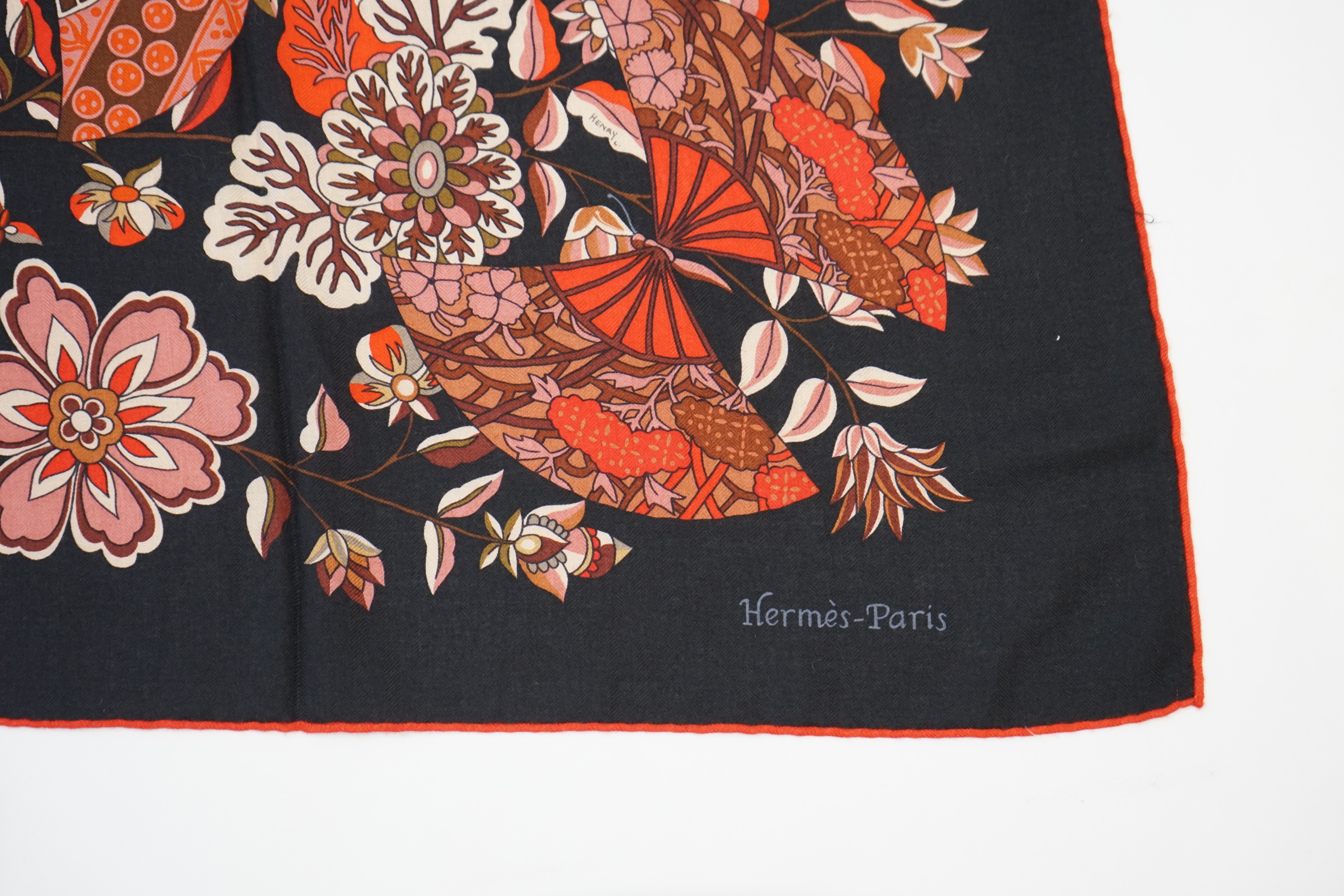 An Hermes wool scarf, with fan and flower motifs on a black ground, in Hermes cloth bag 132 cm.